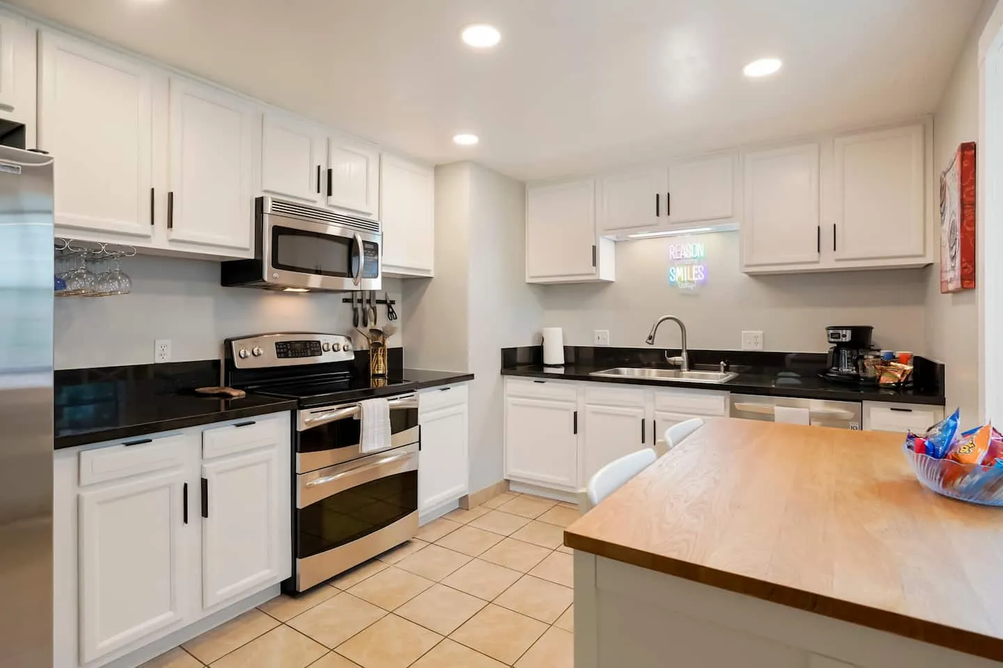 White kitchen with stainless appliances and a butcher-block island