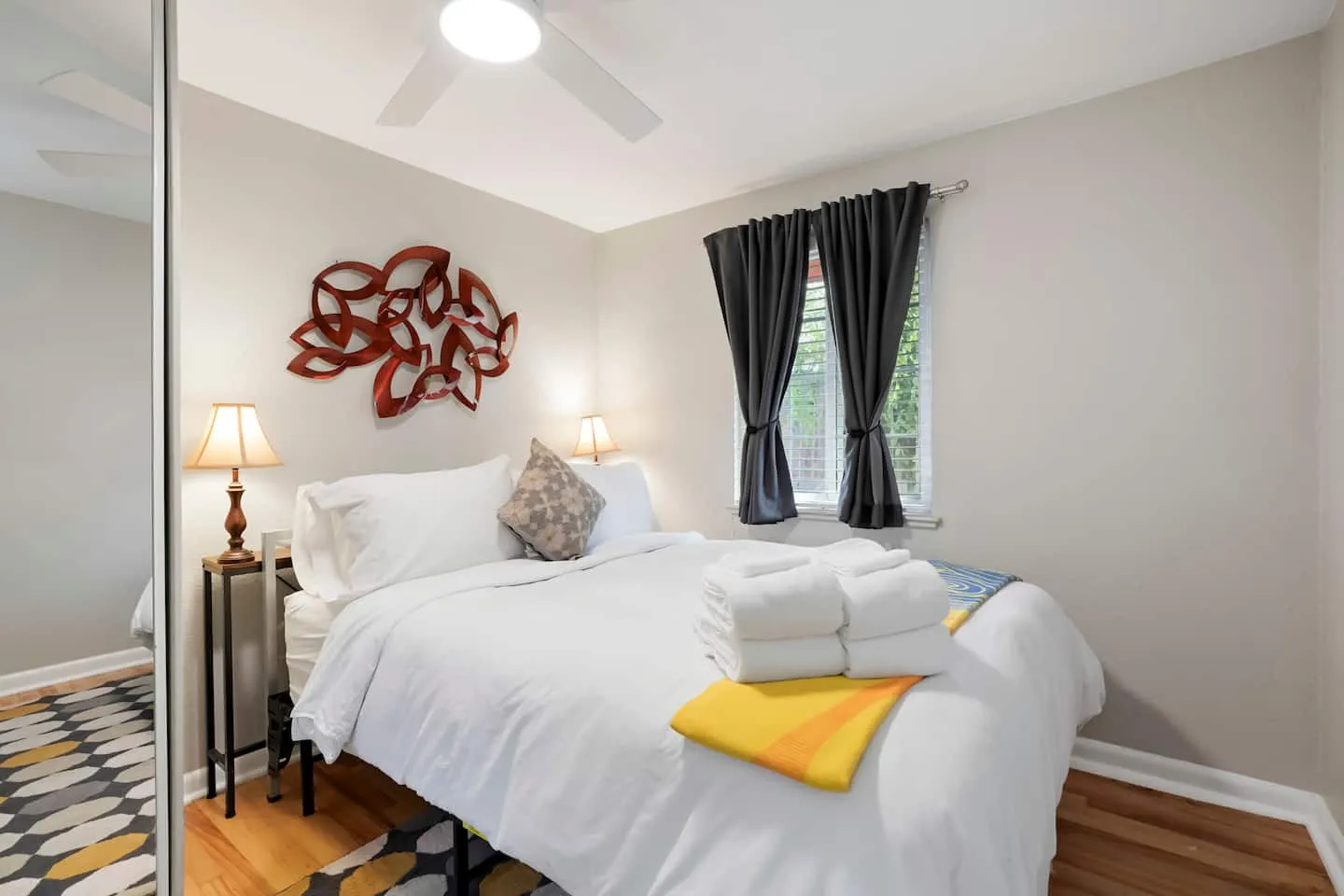 Queen bed with fresh towels and dark curtains